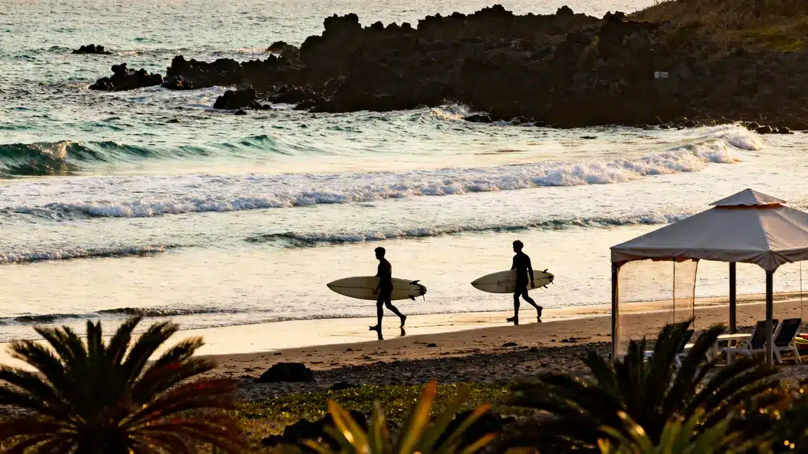 surfeurs sur plage jeju avec vagues et volcan